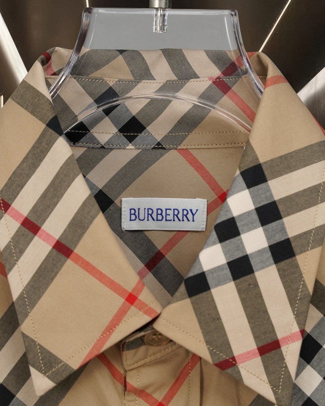 Burberry plaid shirt neckline and logo label on beige fabric with black, red, and gray checks