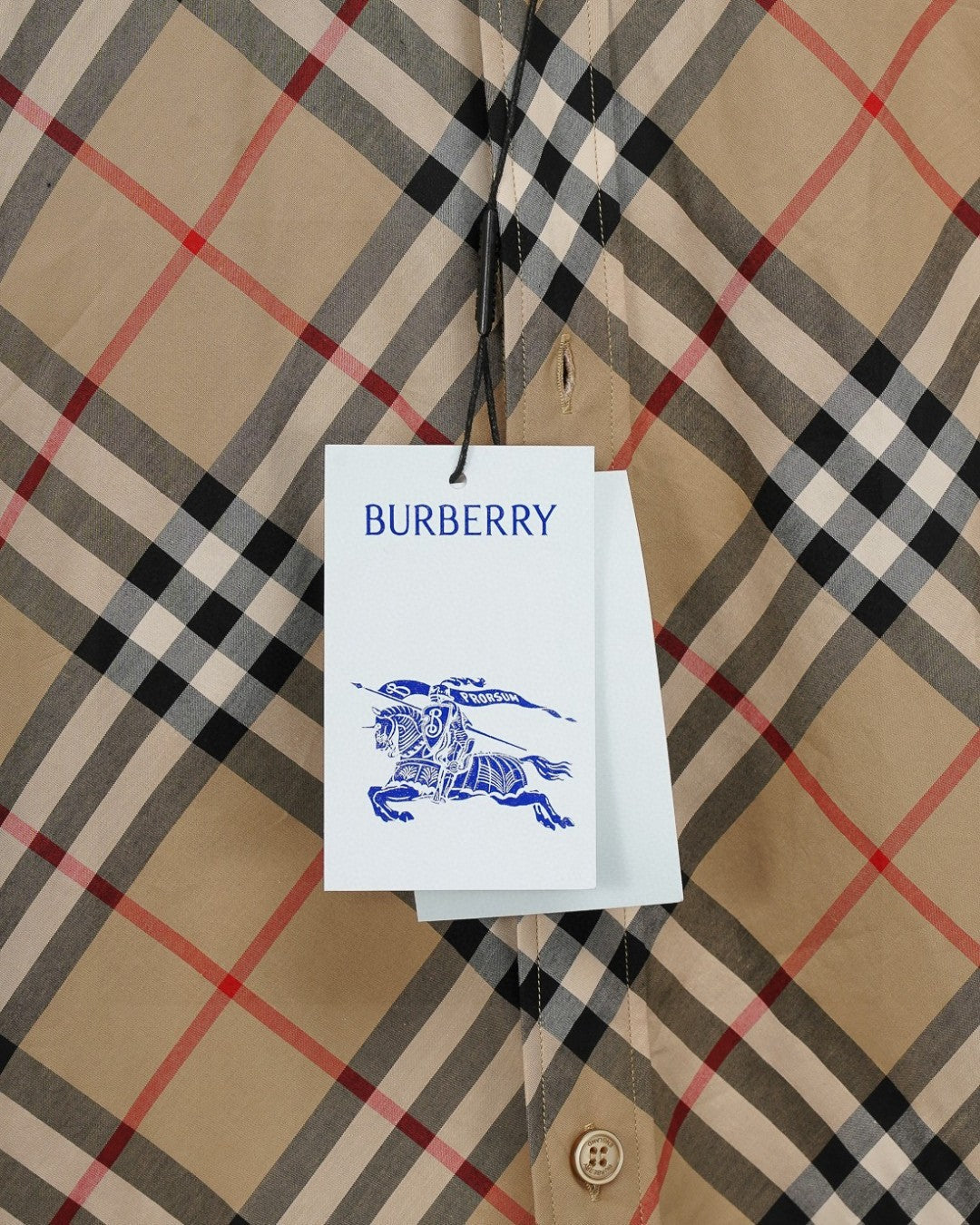 Burberry plaid shirt hang tag on beige fabric with black and red check pattern