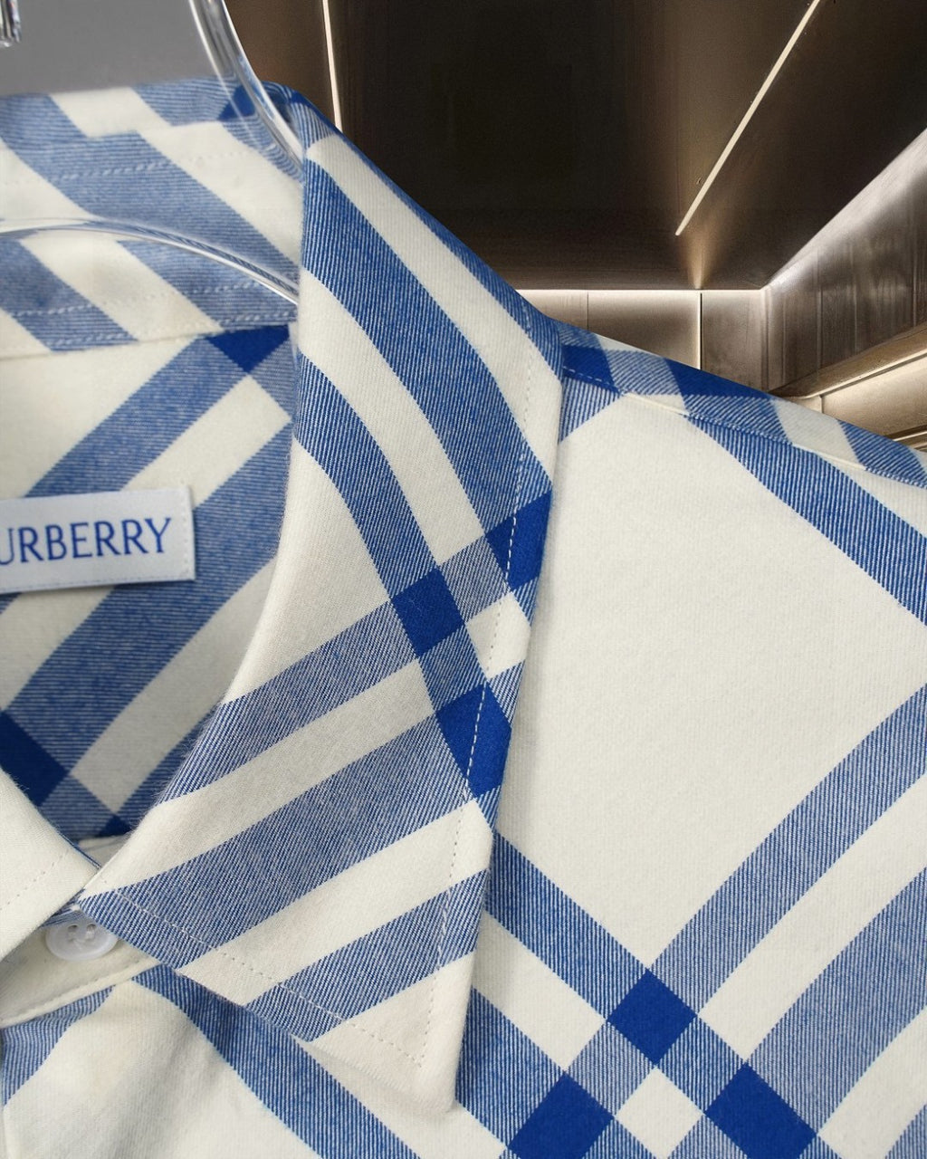 Blue-and-white plaid shirt fabric close-up with buttoned cuff and collar