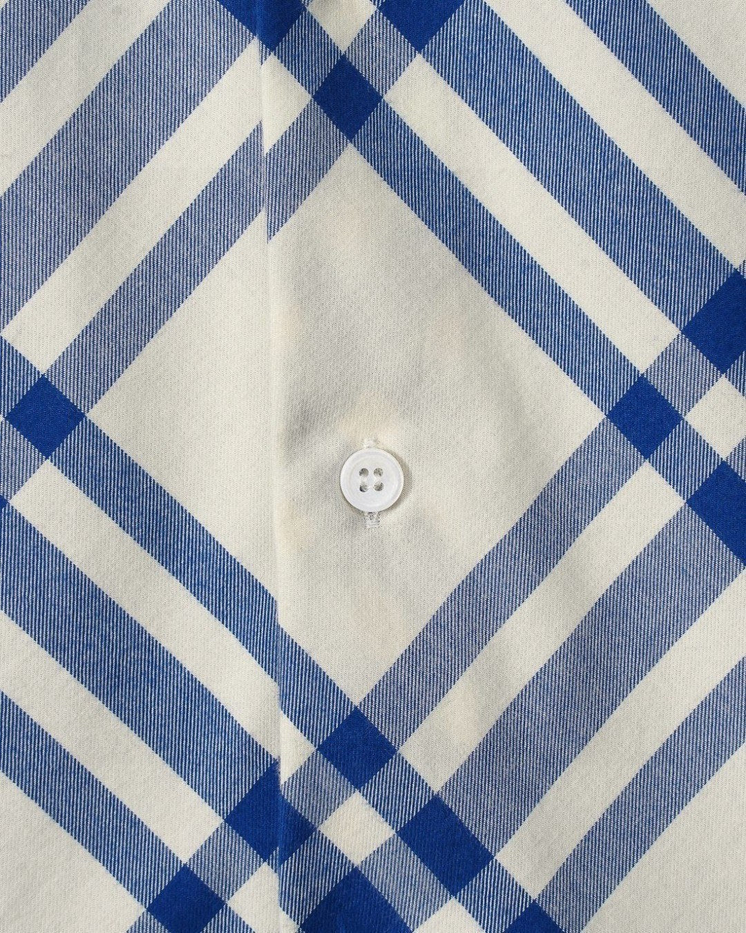 Plaid shirt front detail with button at center and blue-and-white check pattern