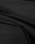 Black quilted fabric close-up with diagonal stitching and layered folds at the seam.