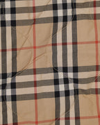 Plaid fabric panel of long coat in beige with black and red checks, visible quilted seams
