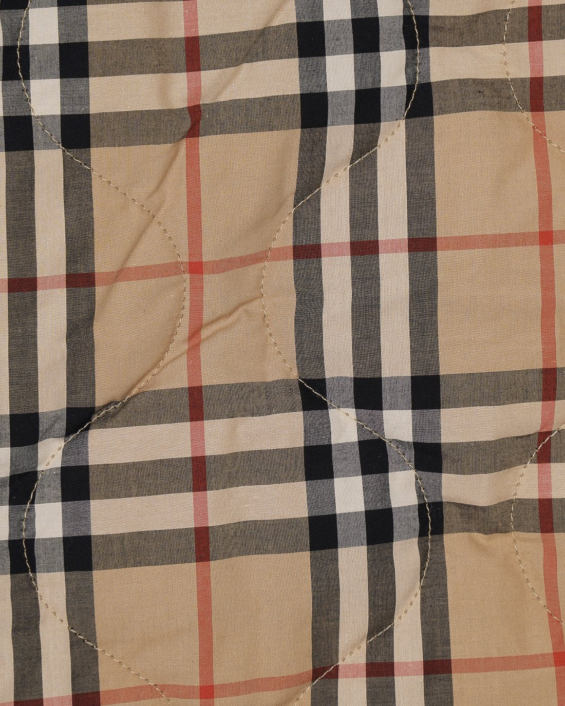 Plaid fabric panel of long coat in beige with black and red checks, visible quilted seams