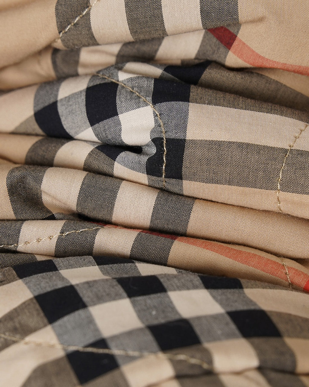 Folded plaid fabric of long coat in beige with black and red checks, textured weave