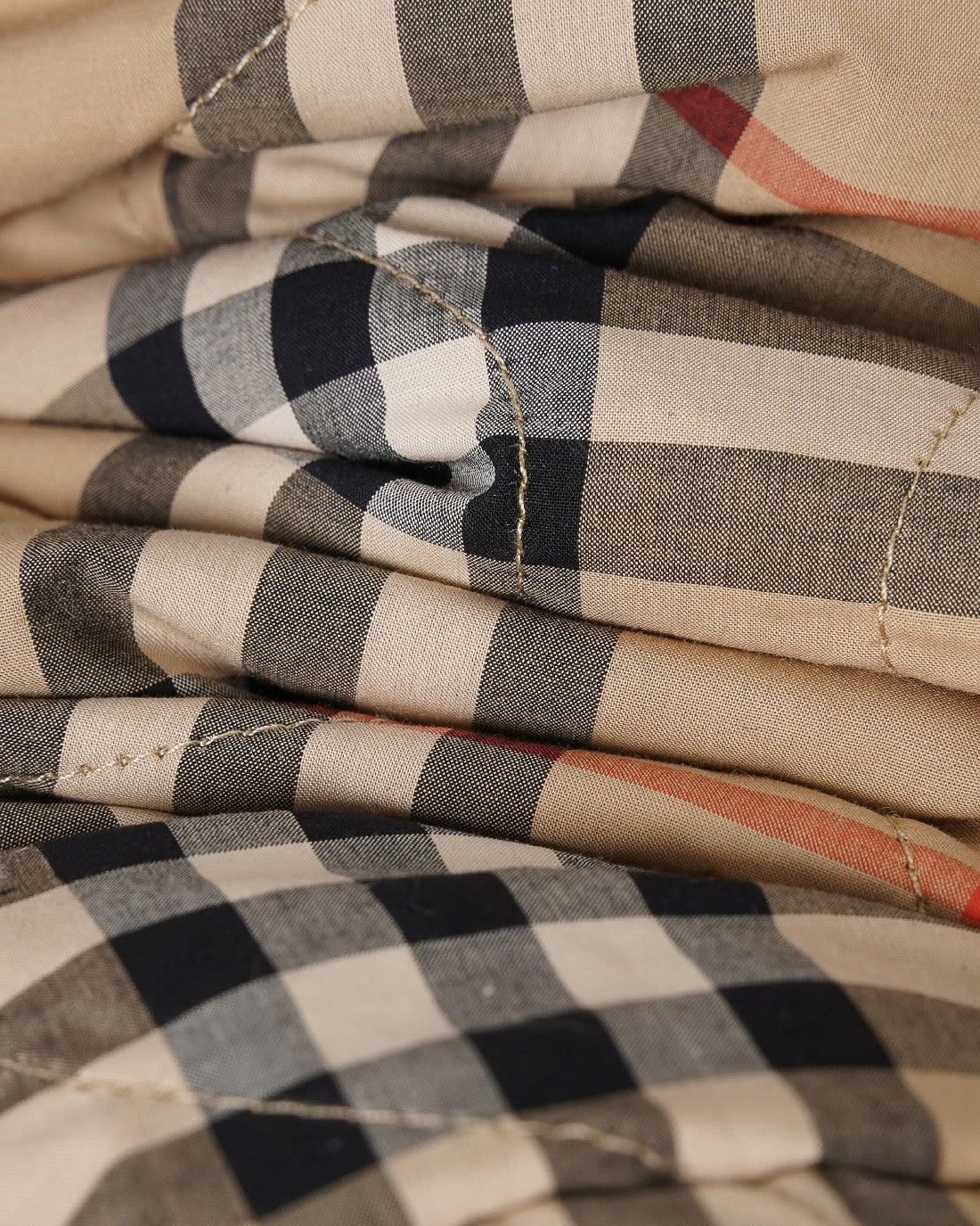 Folded plaid fabric of long coat in beige with black and red checks, textured weave