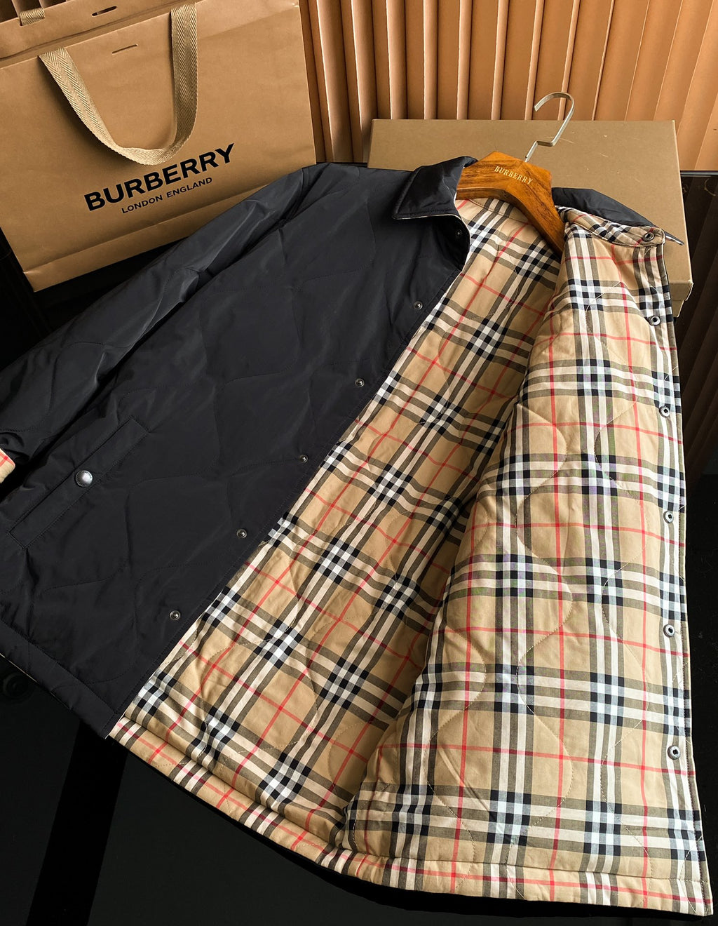 Black long jacket laid open, showing tan red and blue plaid inner lining