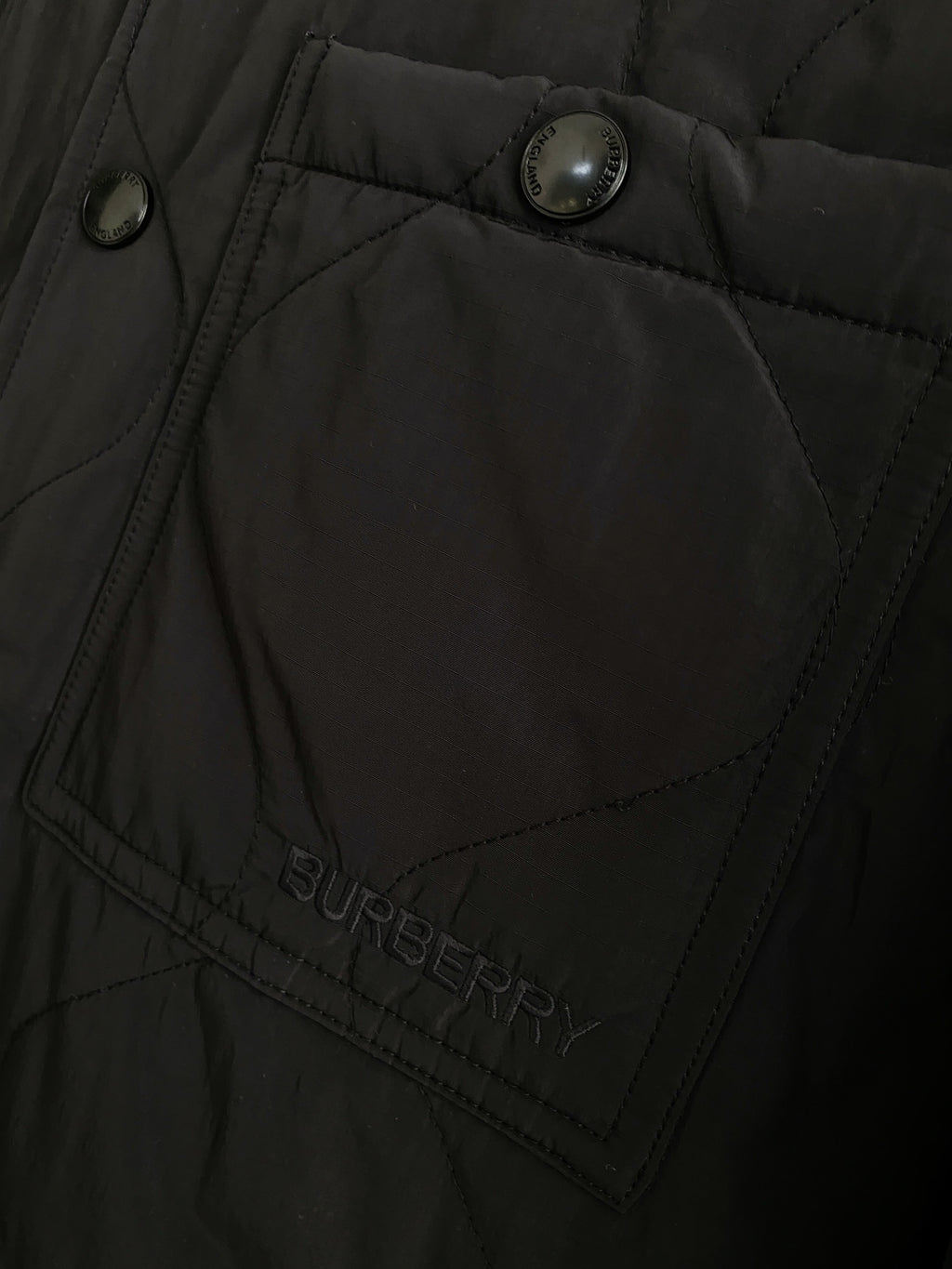 Black jacket panel with quilted stitching and Burberry logo patch