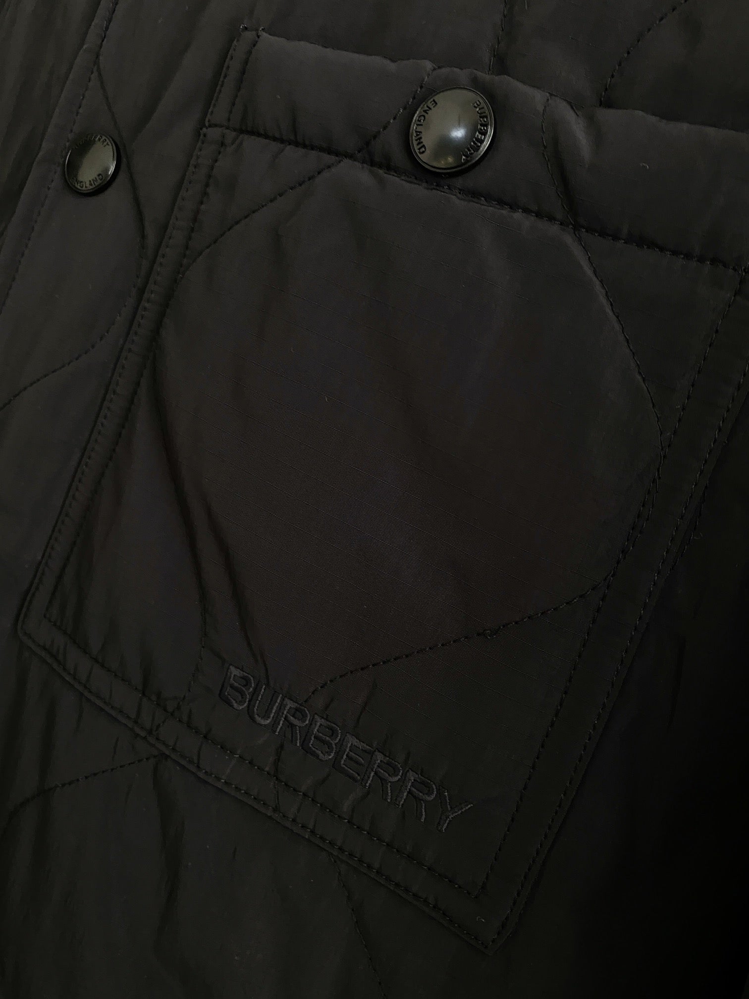 Black jacket panel with quilted stitching and Burberry logo patch