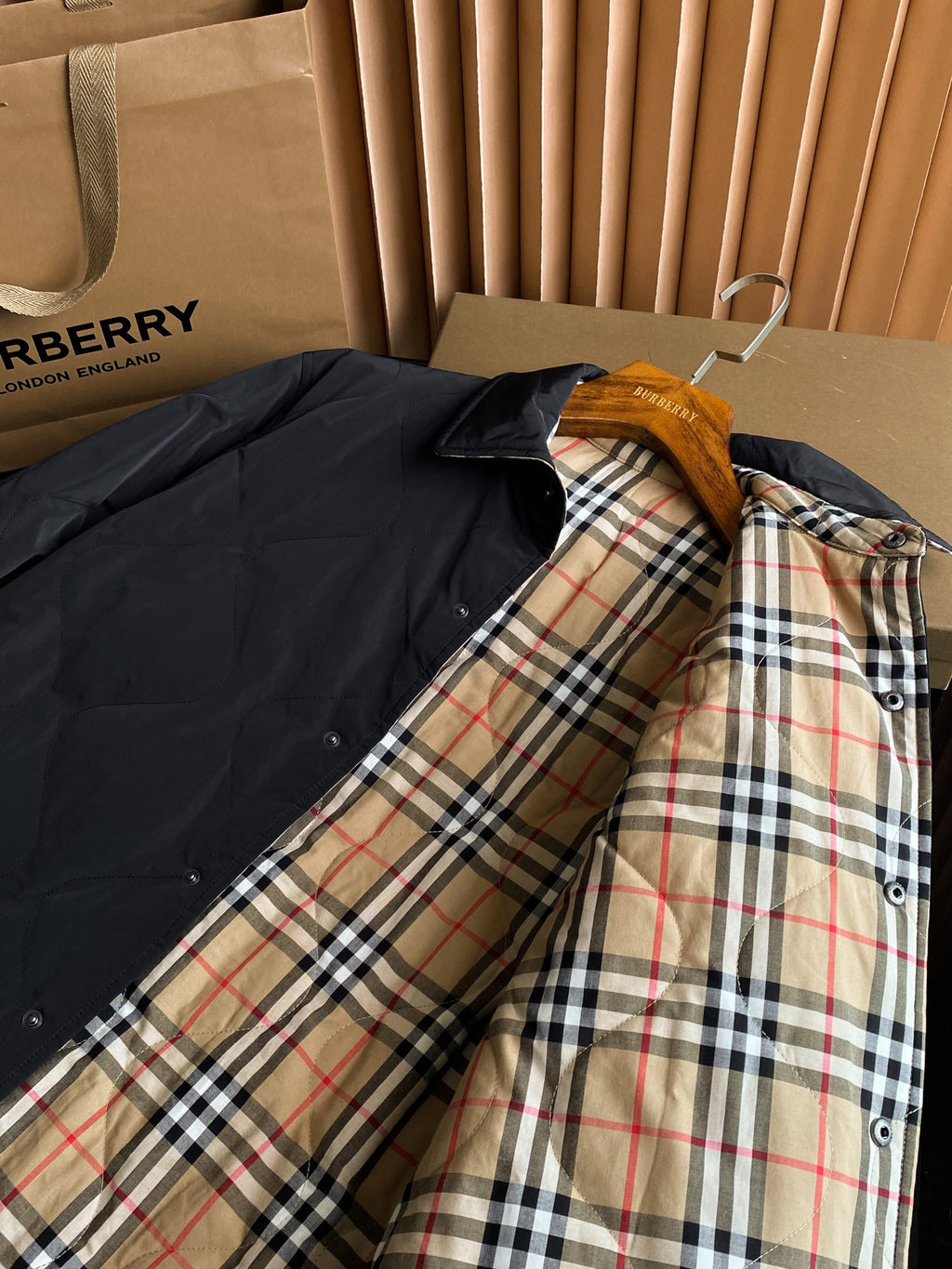 Black long jacket on hanger with tan red and blue plaid inner lining