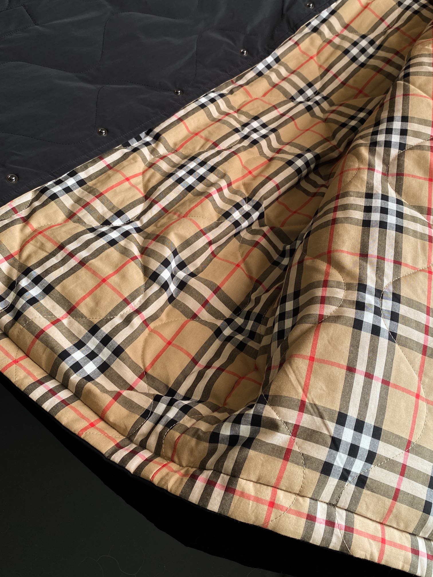 Long jacket lining with beige, black, red, and navy plaid panel and stitched hem