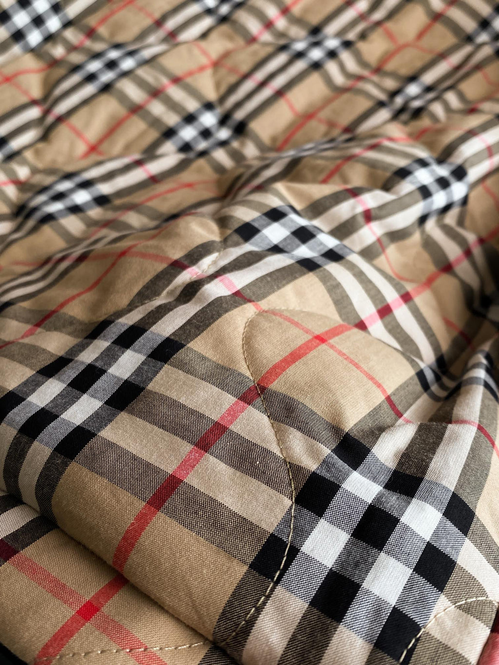 Plaid fabric close-up lining in beige, black, red, and navy with stitching
