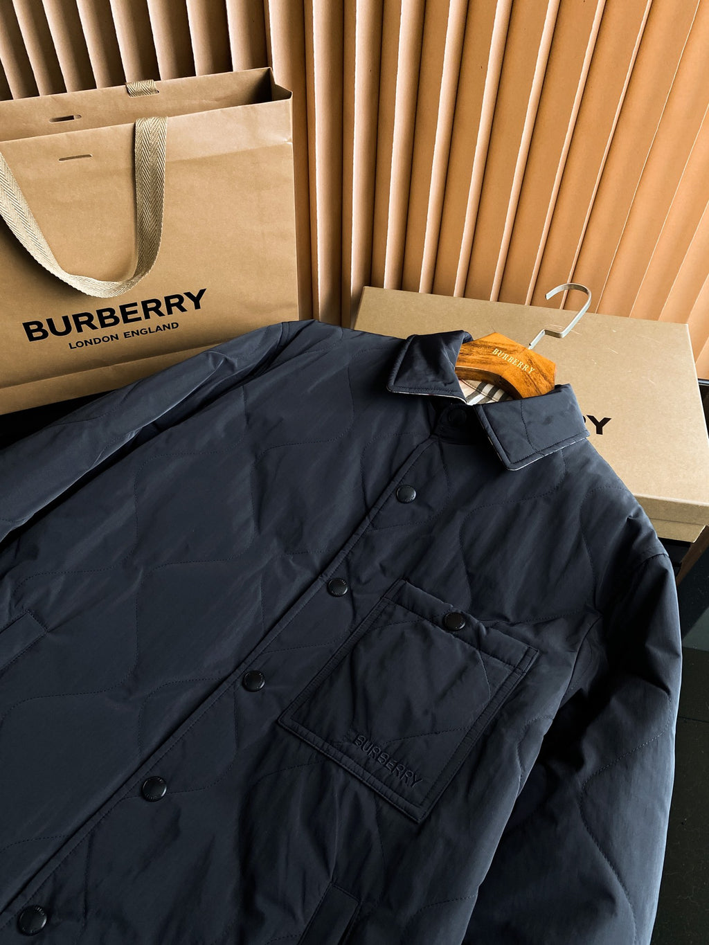 Black long quilted jacket close-up of button placket and chest flap pocket