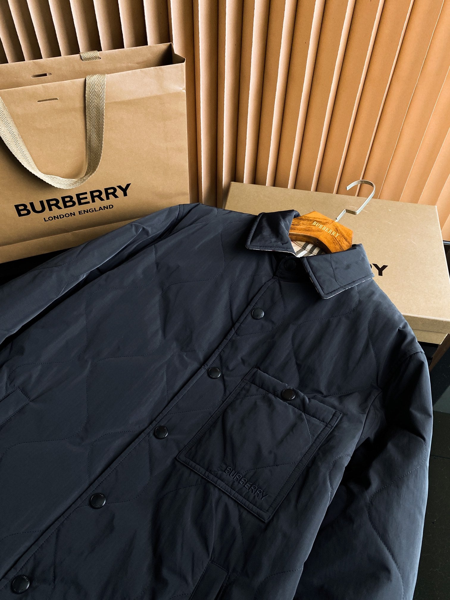 Black long quilted jacket close-up of button placket and chest flap pocket