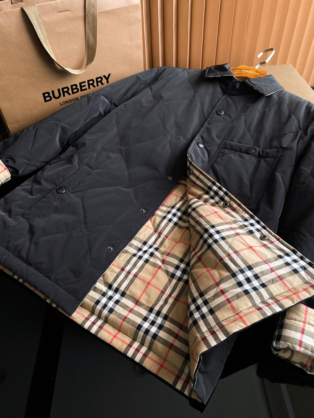 Black long quilted jacket with plaid lining at cuffs and inner placket