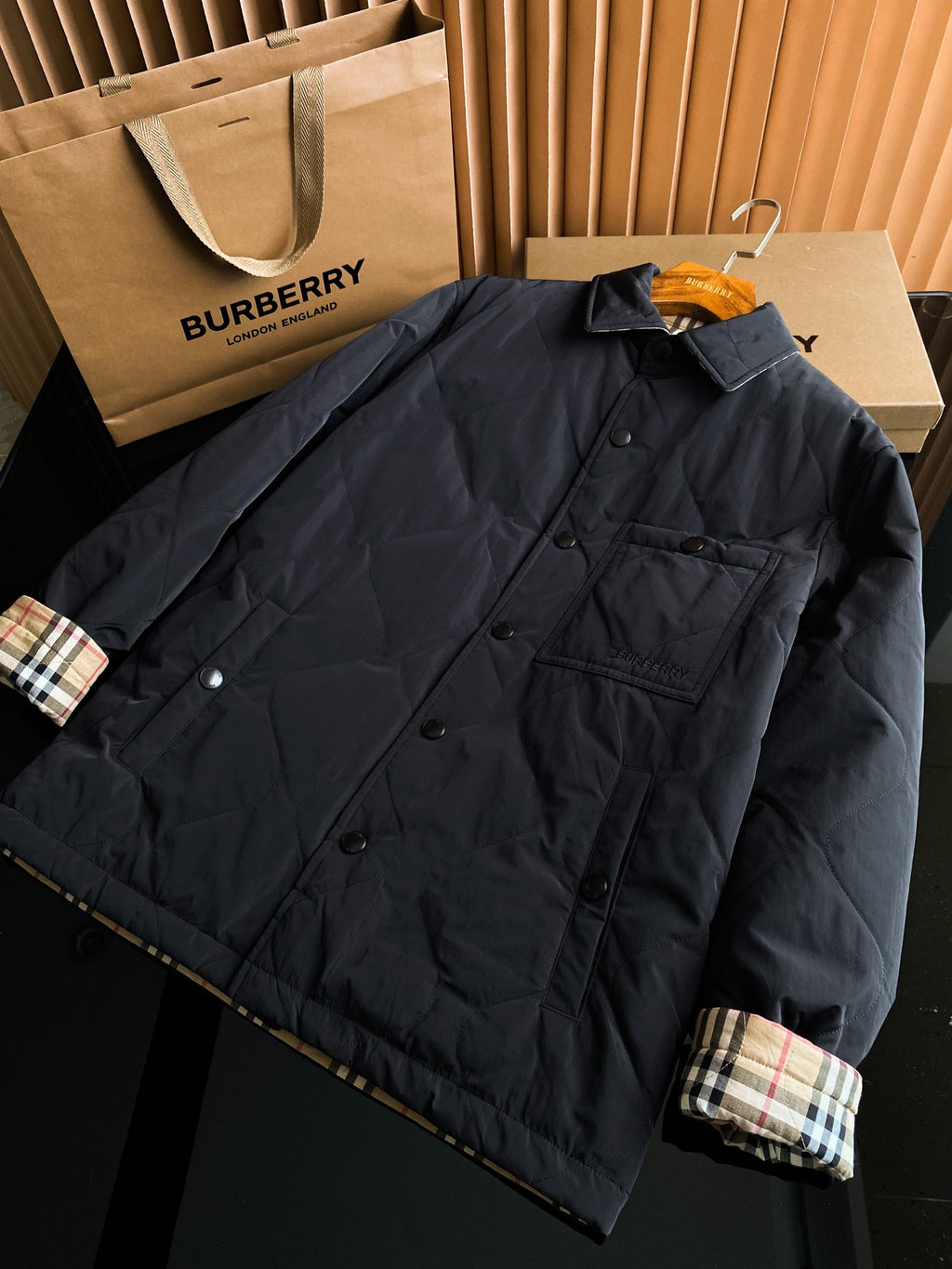 Black long jacket with button front, chest flap pocket, and plaid cuff
