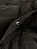 Burberry long coat fabric close-up with dark buttons and stitched pocket detailing.