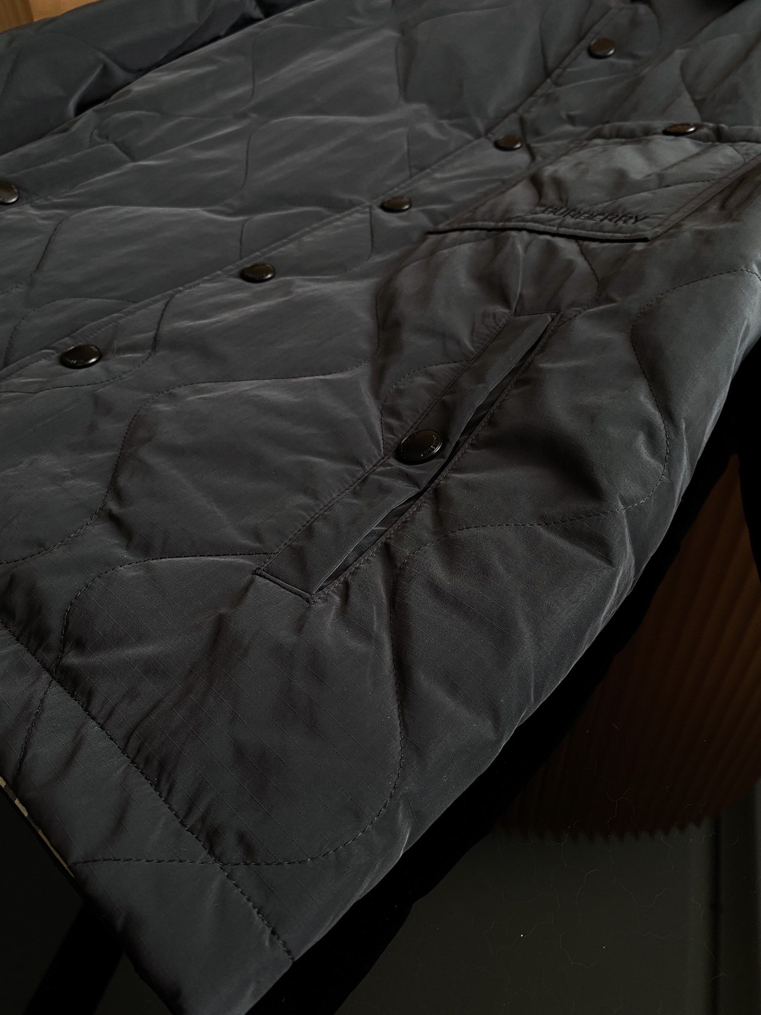 Burberry long quilted coat with diamond stitching, buttoned pocket flap and side seam.