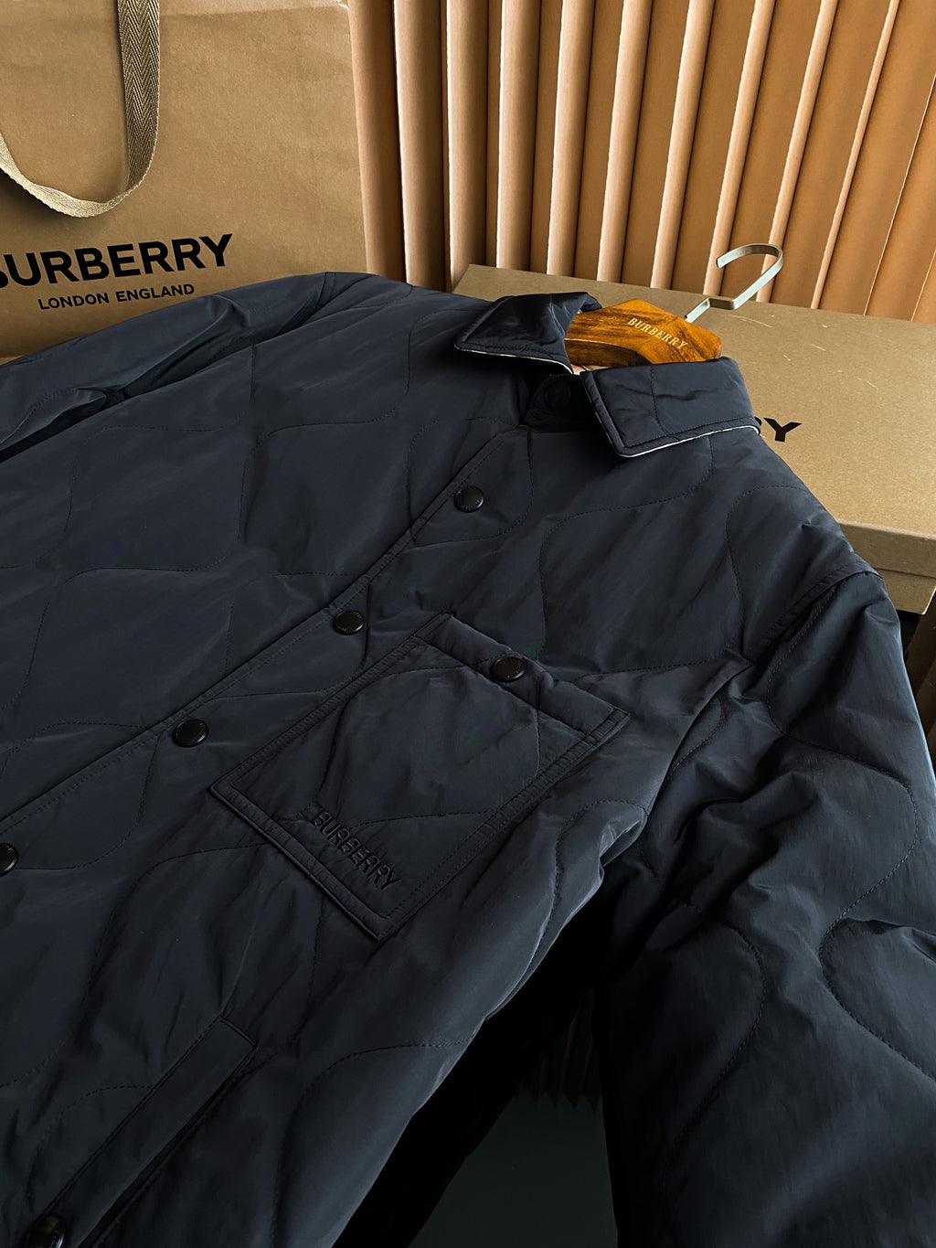Burberry long quilted coat with stand collar and button placket, dark outer fabric.
