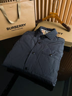 Burberry long quilted coat on hanger, dark color, button front, Burberry logo at hem.