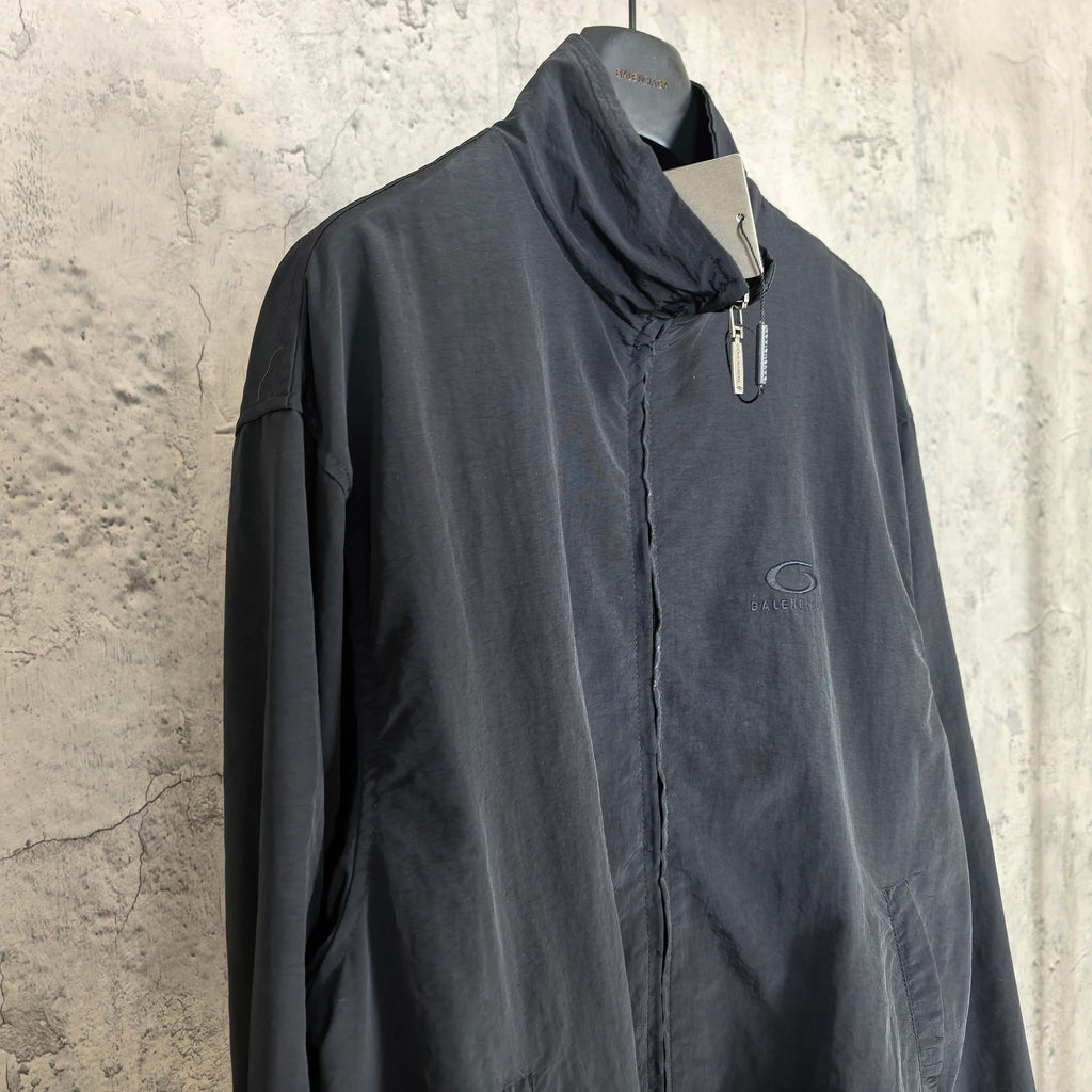 Black Balenciaga zip-up jacket with high collar, front zipper, and oval chest logo.