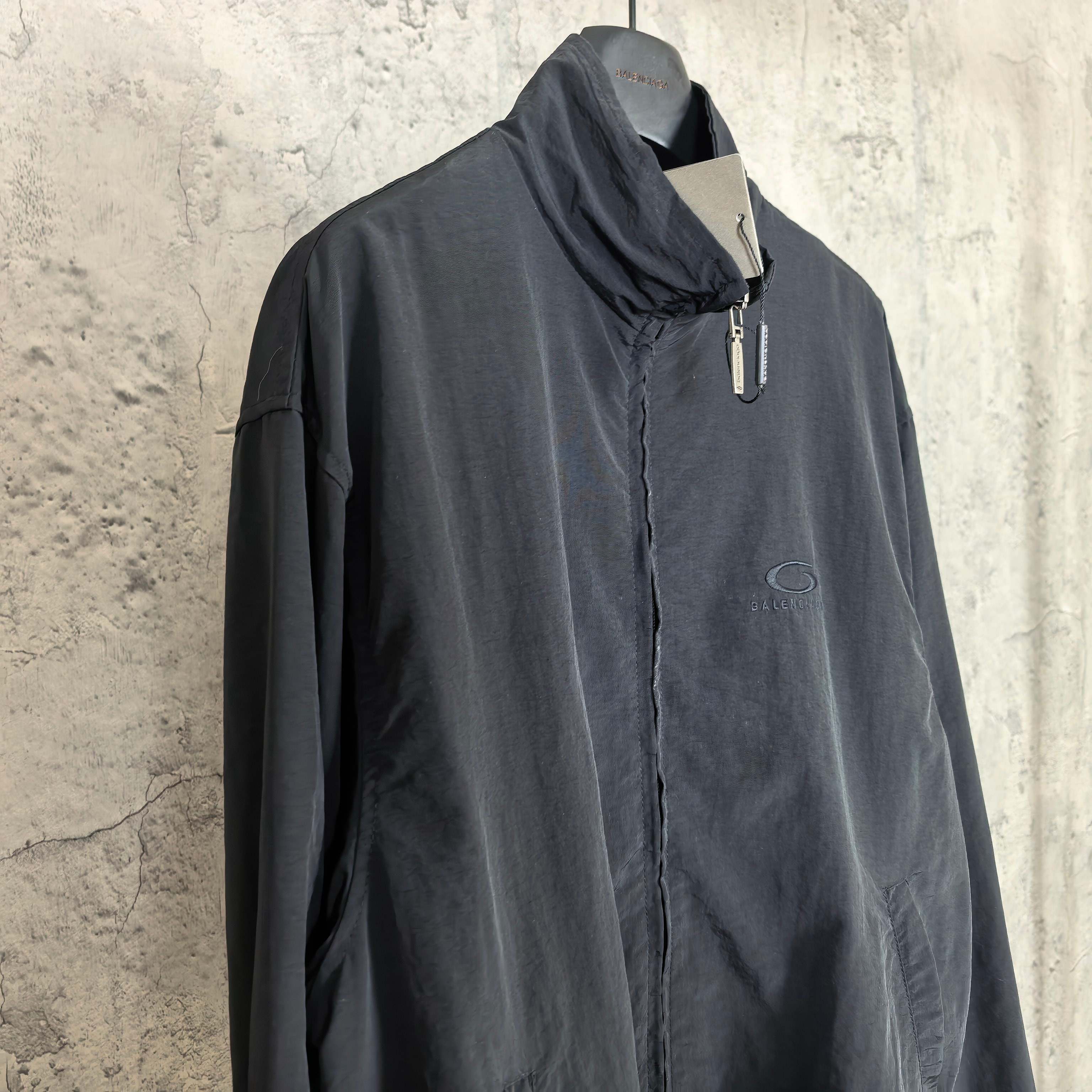 Black Balenciaga zip-up jacket with high collar, front zipper, and oval chest logo.