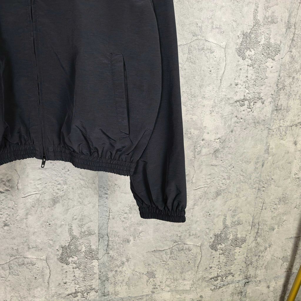 Black zip-up jacket with ribbed elastic hem and cuff, visible lower front zipper.