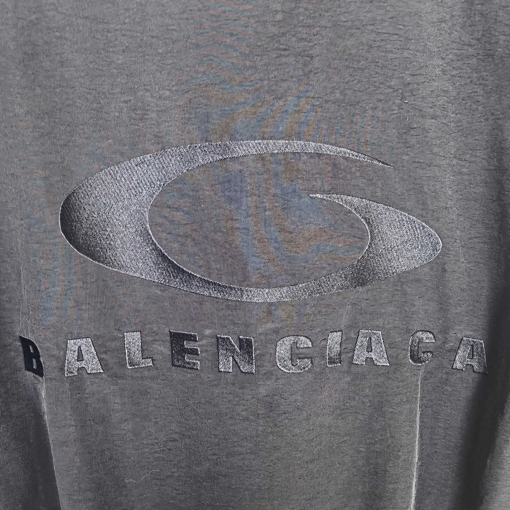 Gray oval logo and BALENCIAGA lettering on dark jacket fabric.