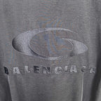 Gray oval logo and BALENCIAGA lettering on dark jacket fabric.