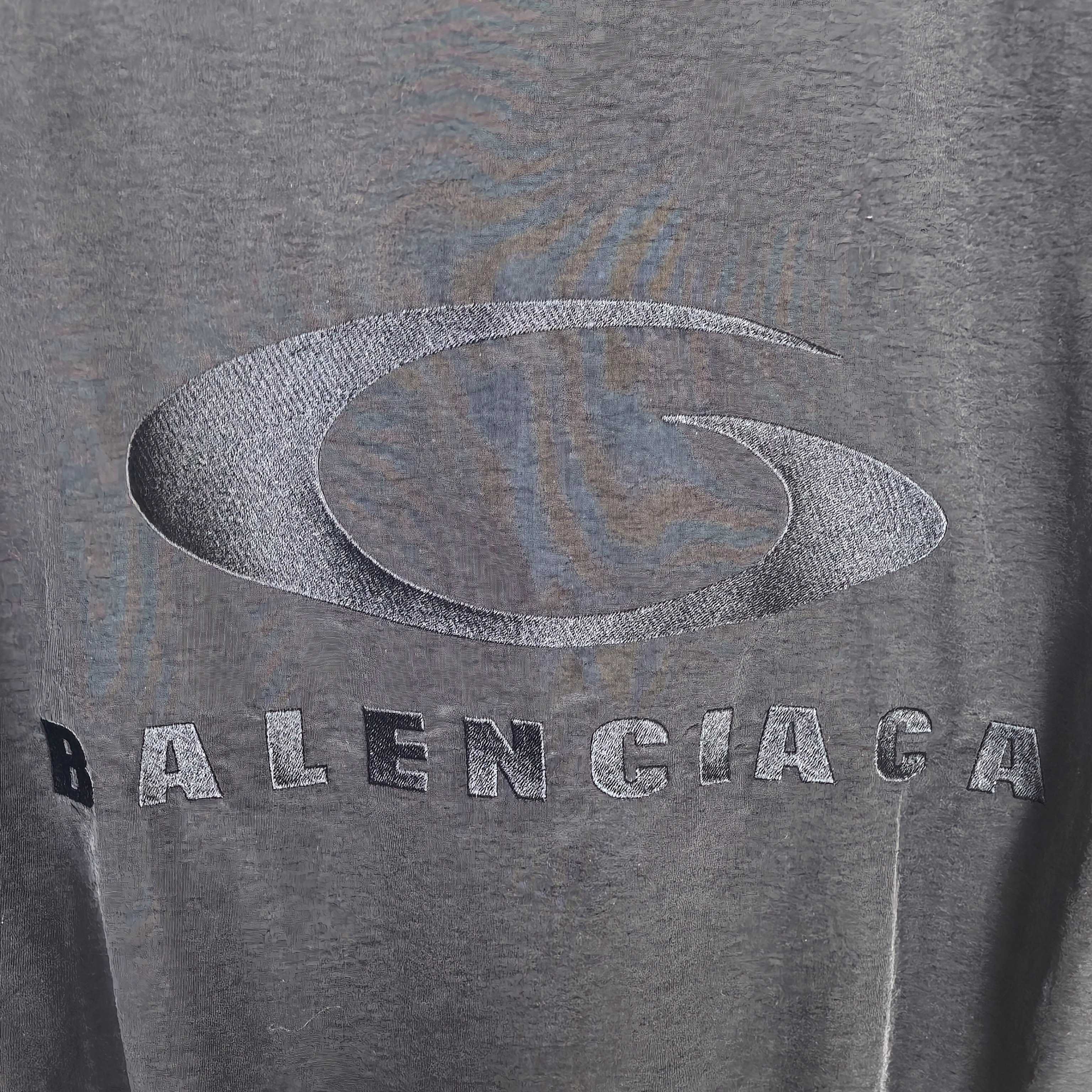 Gray oval logo and BALENCIAGA lettering on dark jacket fabric.