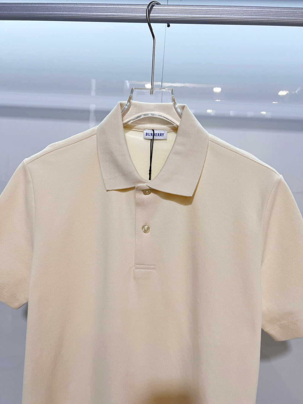 Burberry short-sleeve polo shirt in light cream, close-up of collar and button placket