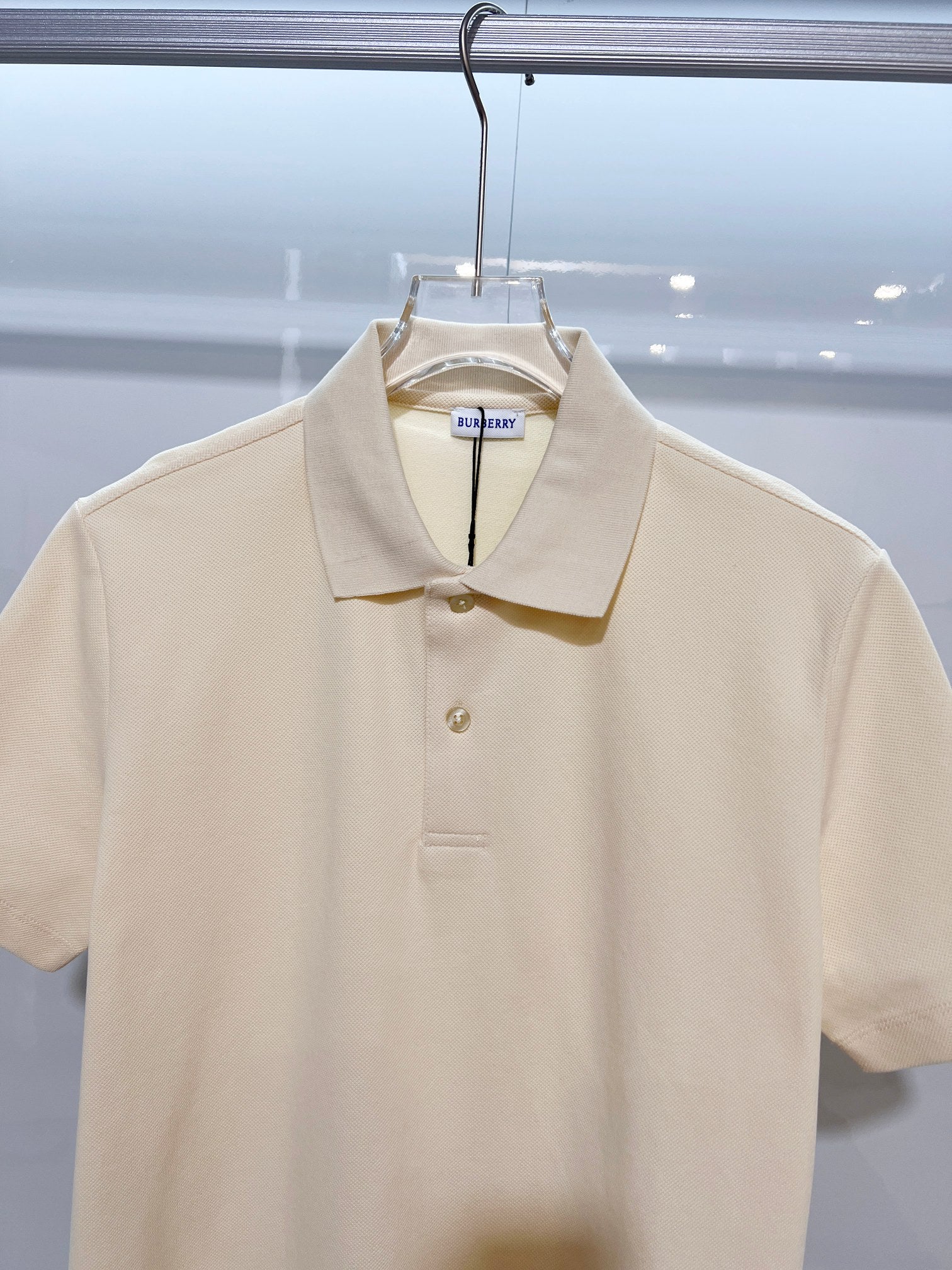 Burberry short-sleeve polo shirt in light cream, close-up of collar and button placket