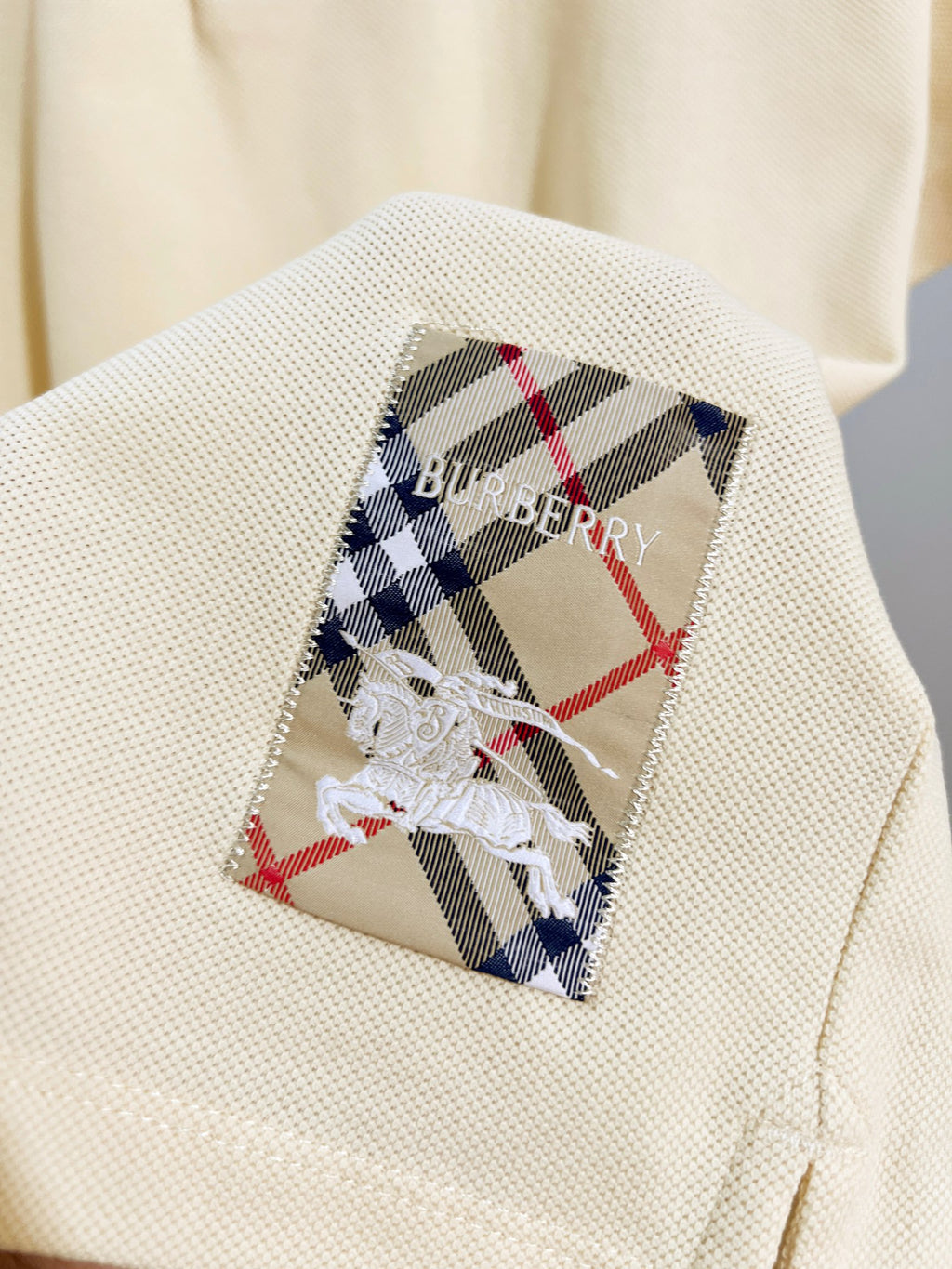 Burberry short-sleeve polo shirt in light cream, chest patch with check pattern and bow