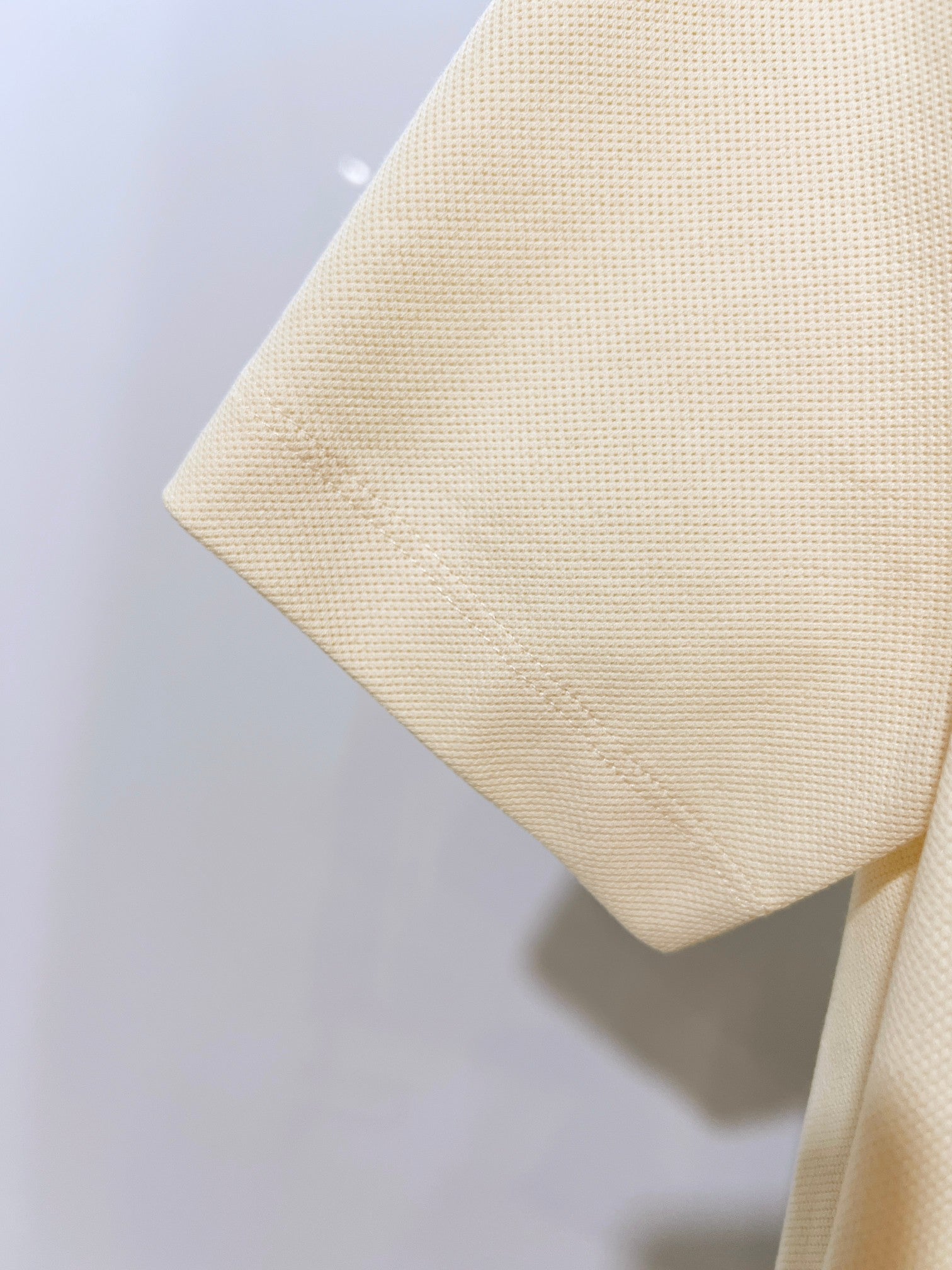 Burberry short-sleeve polo shirt in light cream, side view of textured fabric