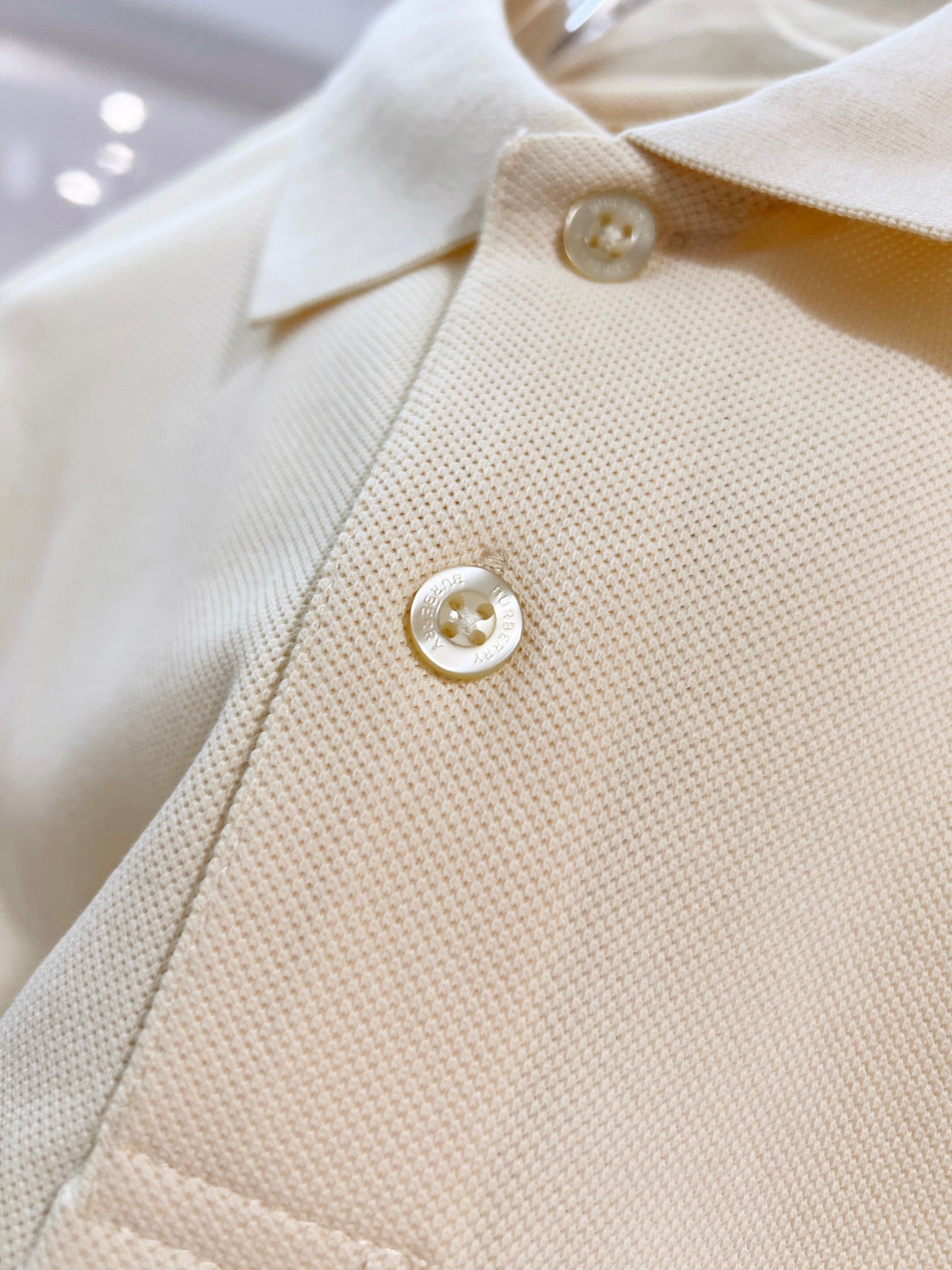 Burberry short-sleeve polo shirt in light cream, two front buttons on textured knit