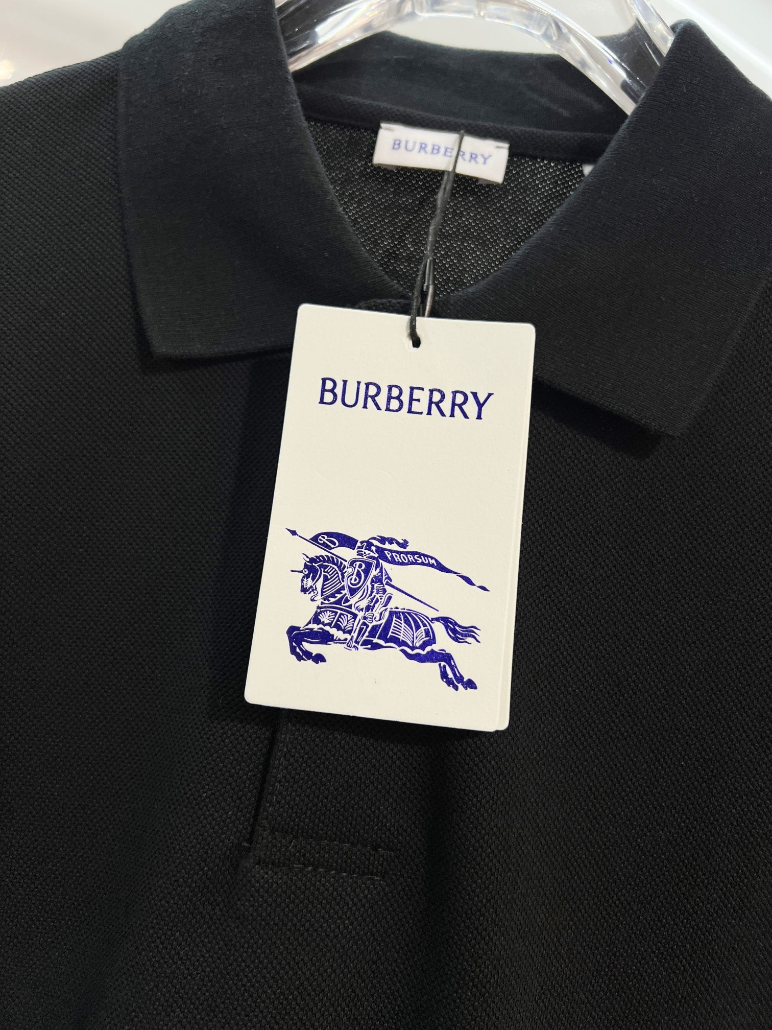 Black polo shirt with Burberry neck tag and blue horse logo on white label