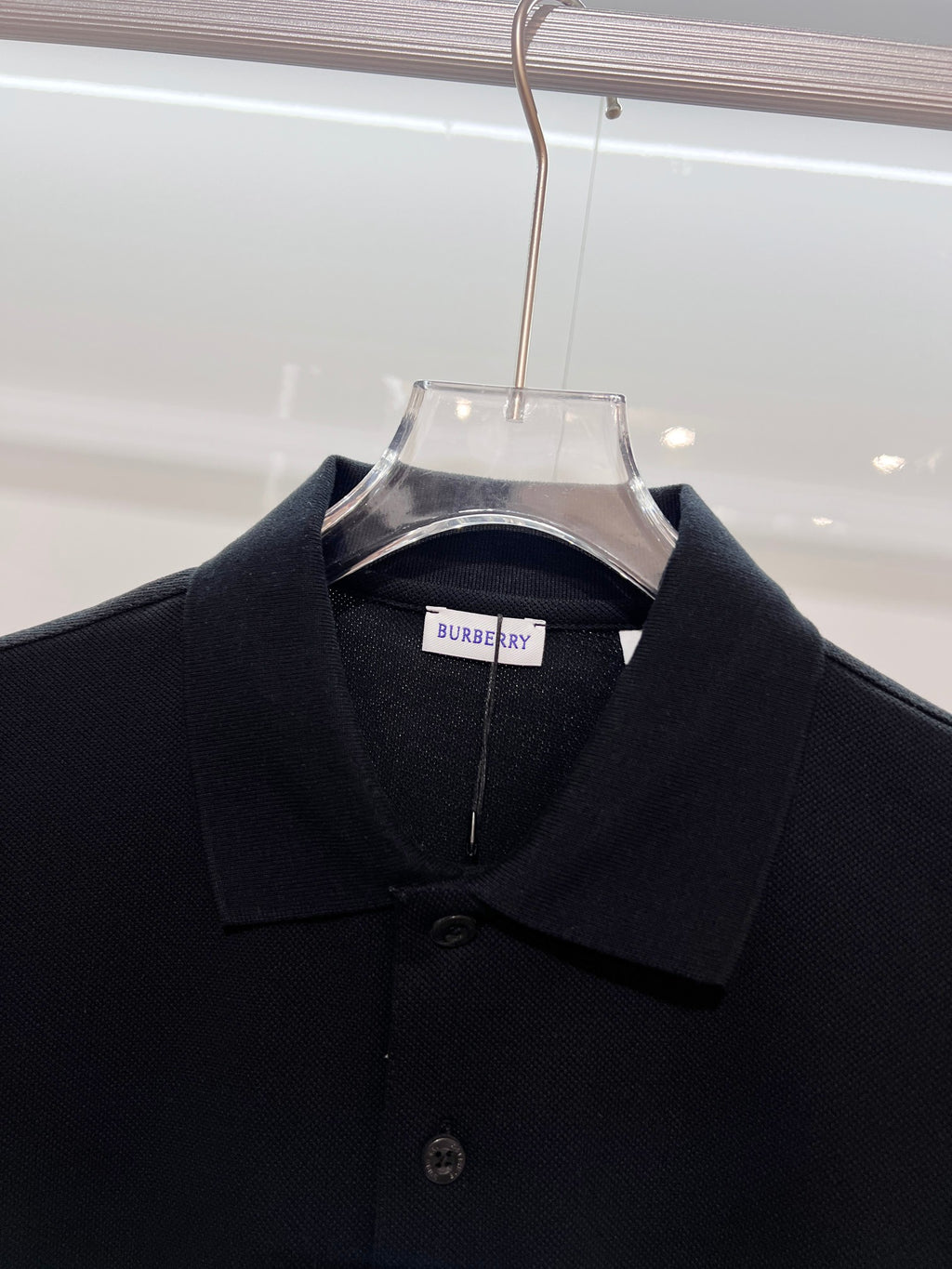 Black polo shirt close-up with Burberry neck label and button placket