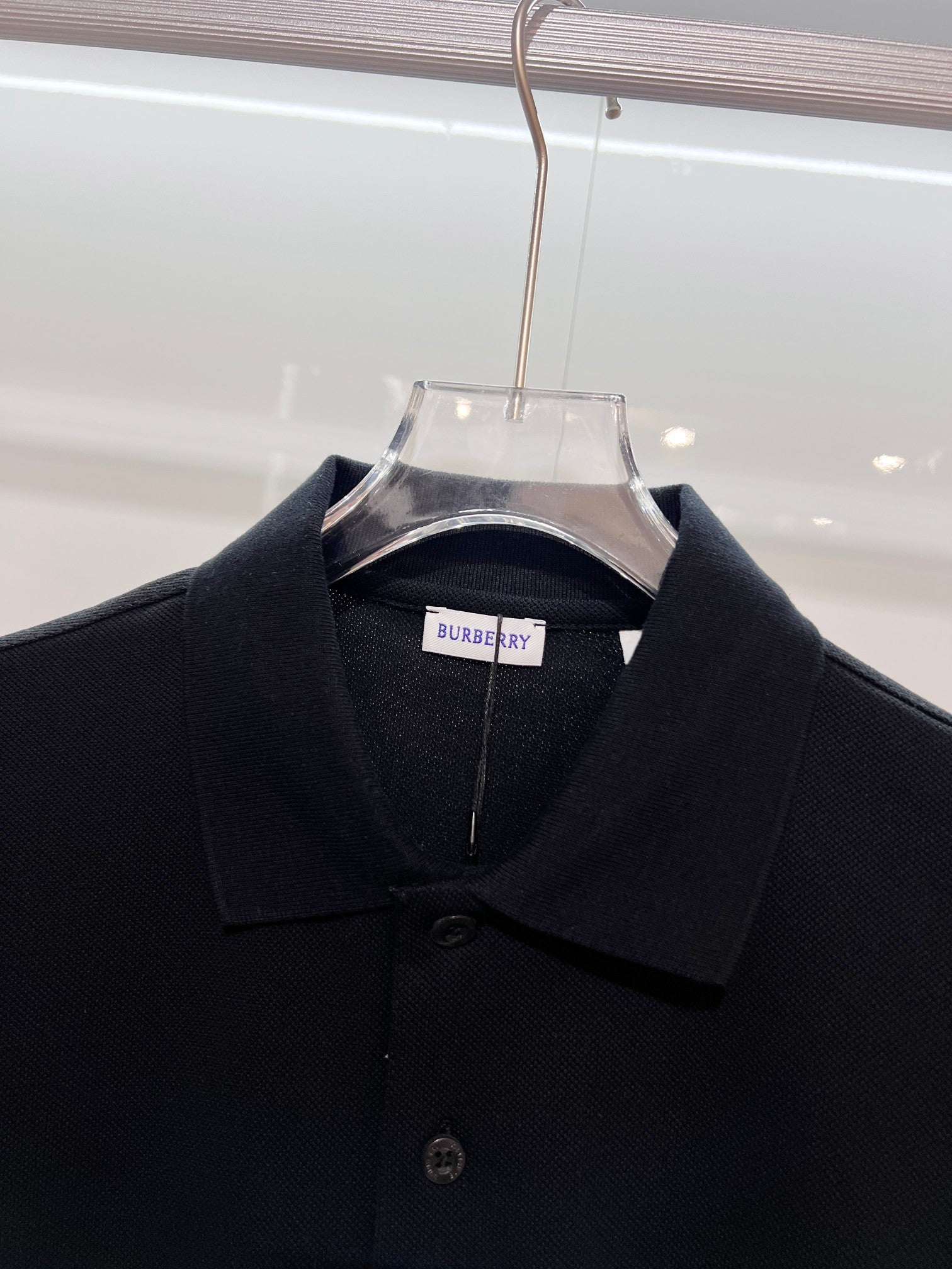 Black polo shirt close-up with Burberry neck label and button placket