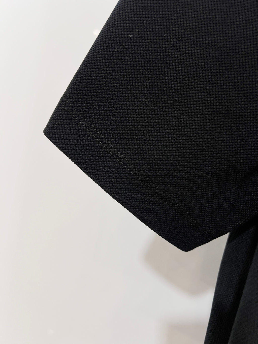 Black textured polo sleeve end with stitched hem