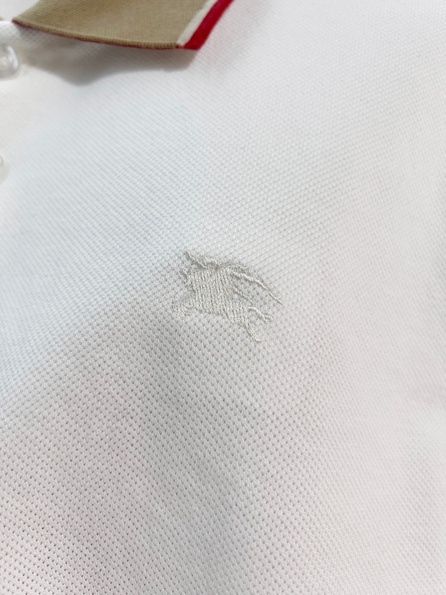 Burberry polo shirt chest with small embroidered logo on white fabric