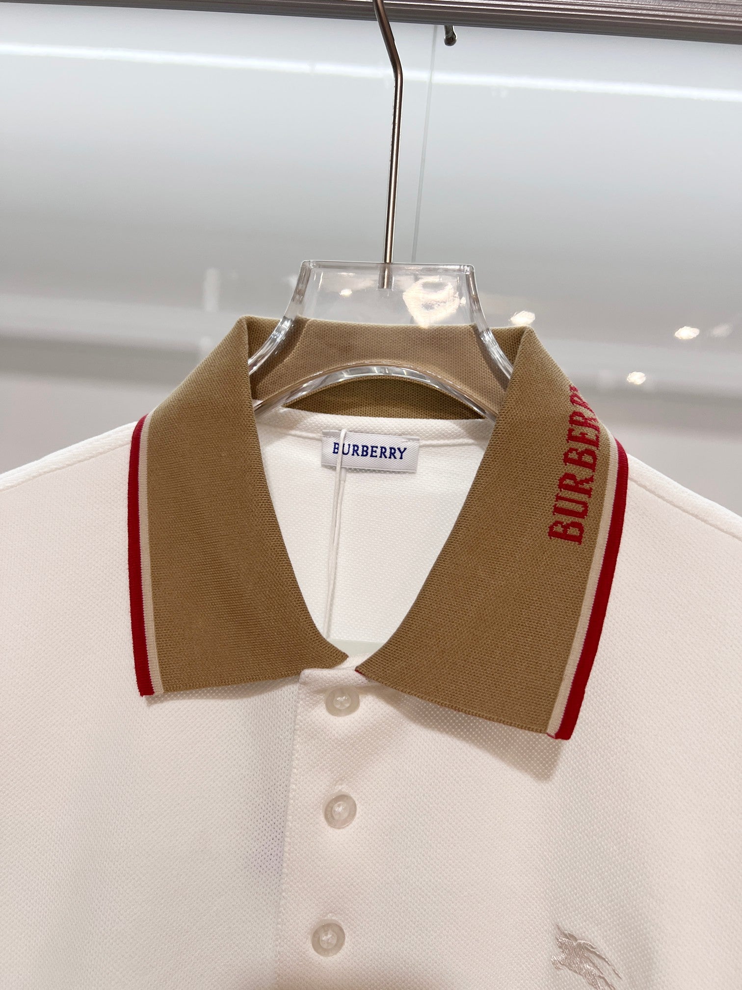 Burberry short-sleeve polo shirt on hanger in white with brown and red collar trim