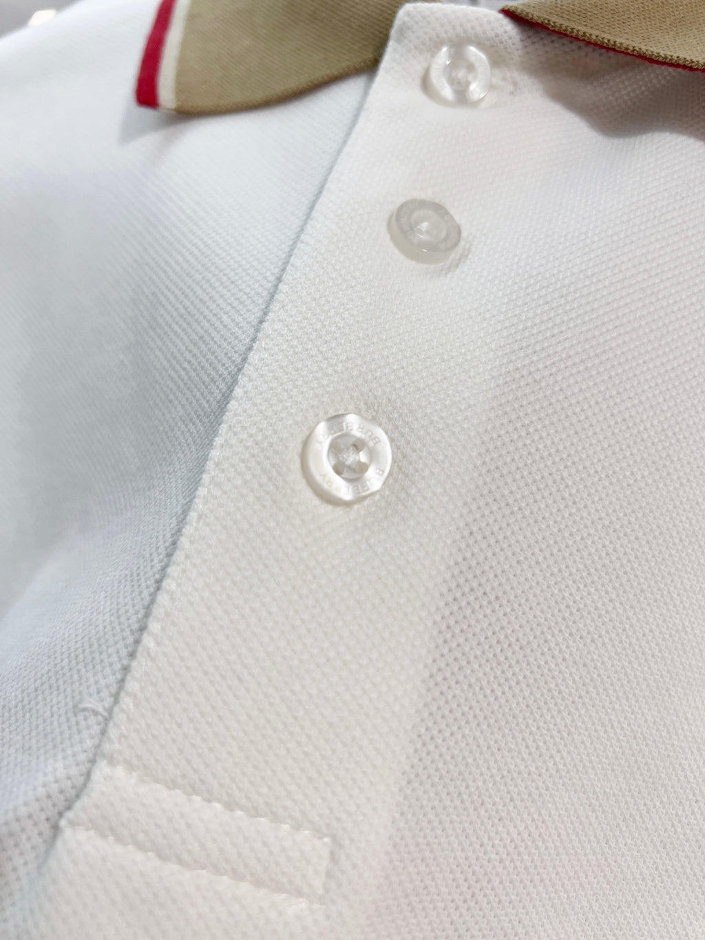 Burberry polo shirt button placket close-up with three white buttons