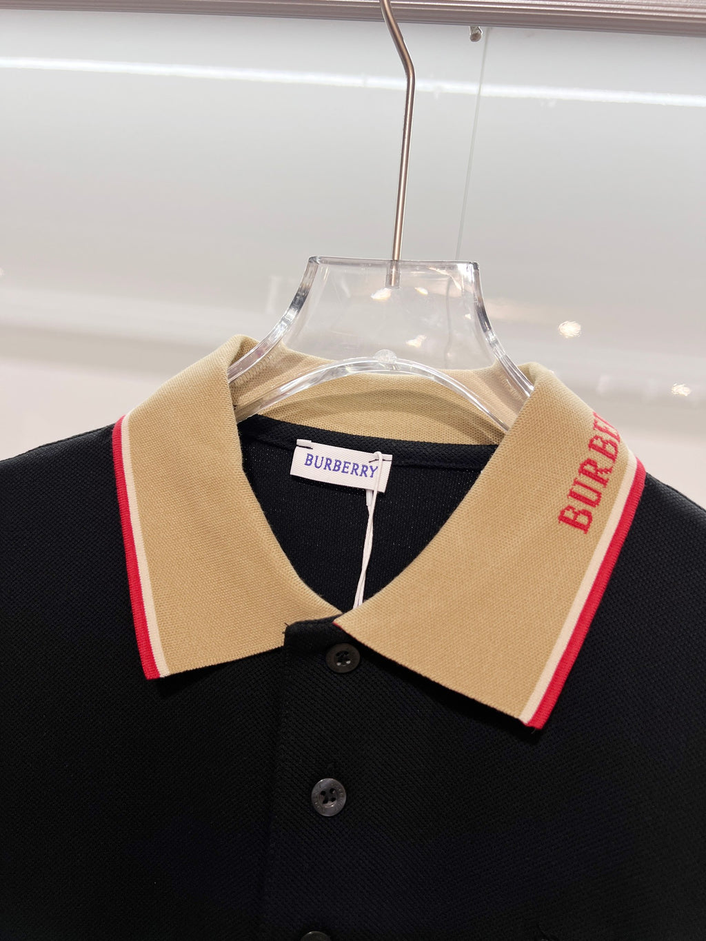 Burberry polo shirt neckline close-up with beige collar and red stripe trim