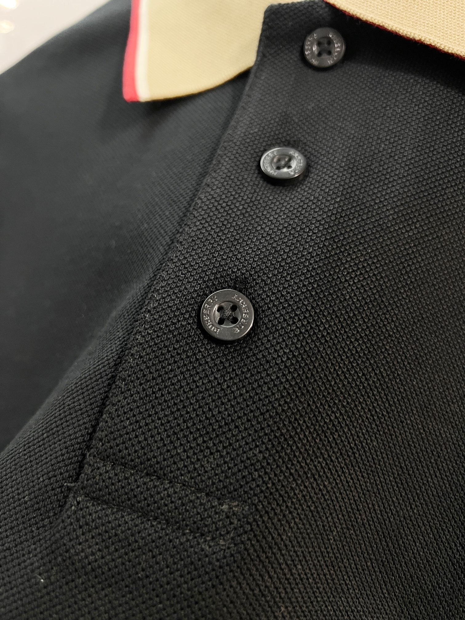 Burberry polo shirt chest close-up with dark navy textured fabric and black buttons