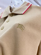 Tan polo shirt close-up of buttons and embroidered horse logo on chest