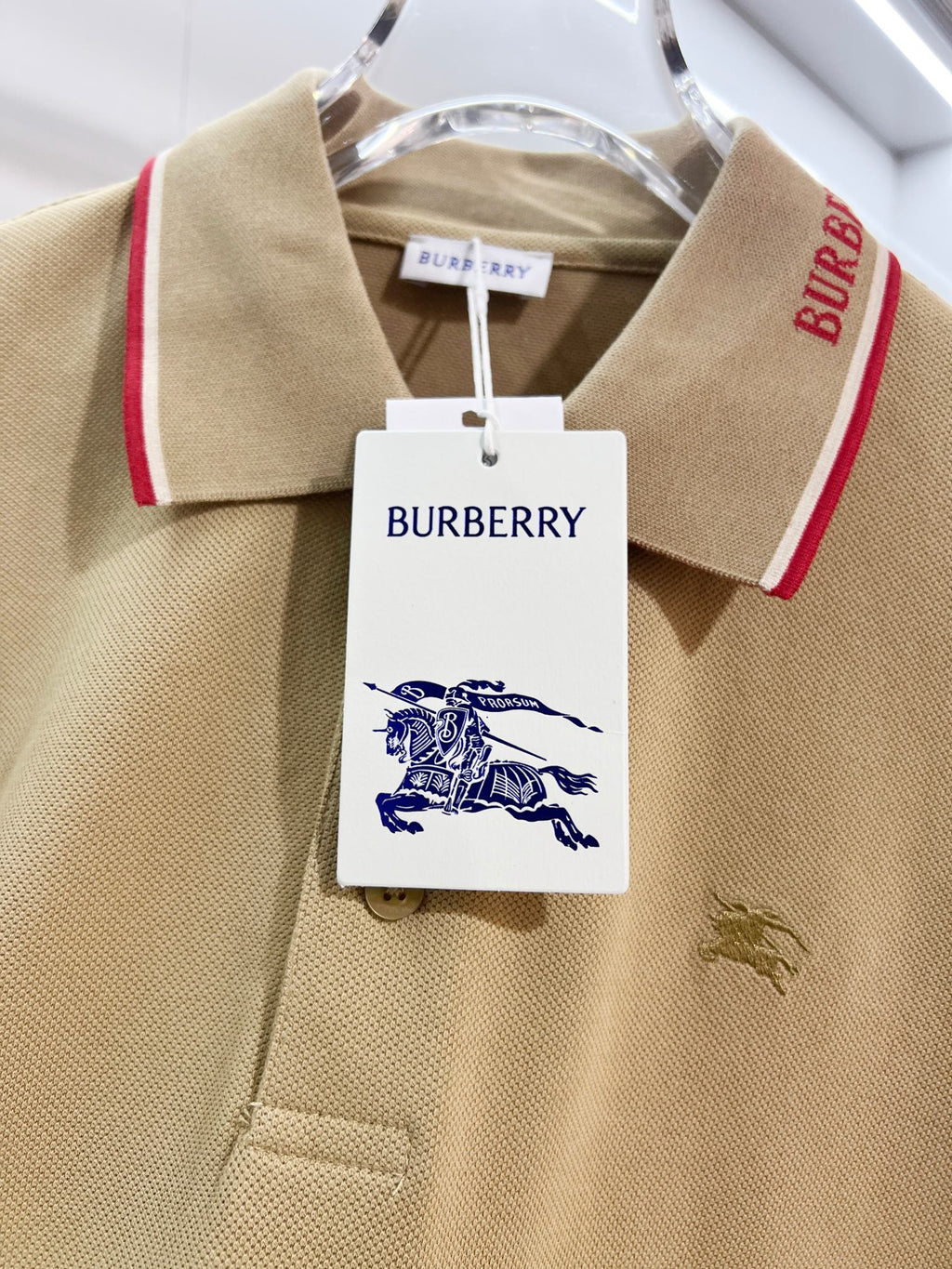 Tan polo shirt close-up of collar tag, red trim, and small horse logo