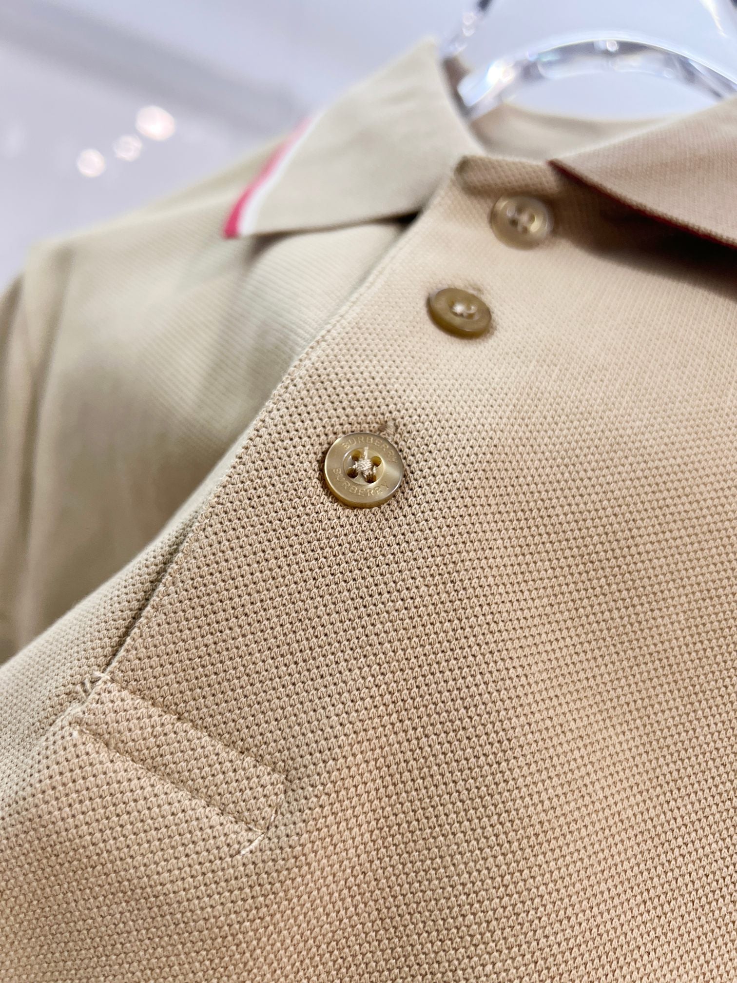 Tan polo shirt close-up of button placket with two gold buttons