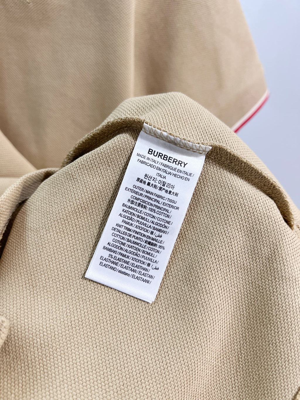 Tan polo shirt care label inside collar with text and size info
