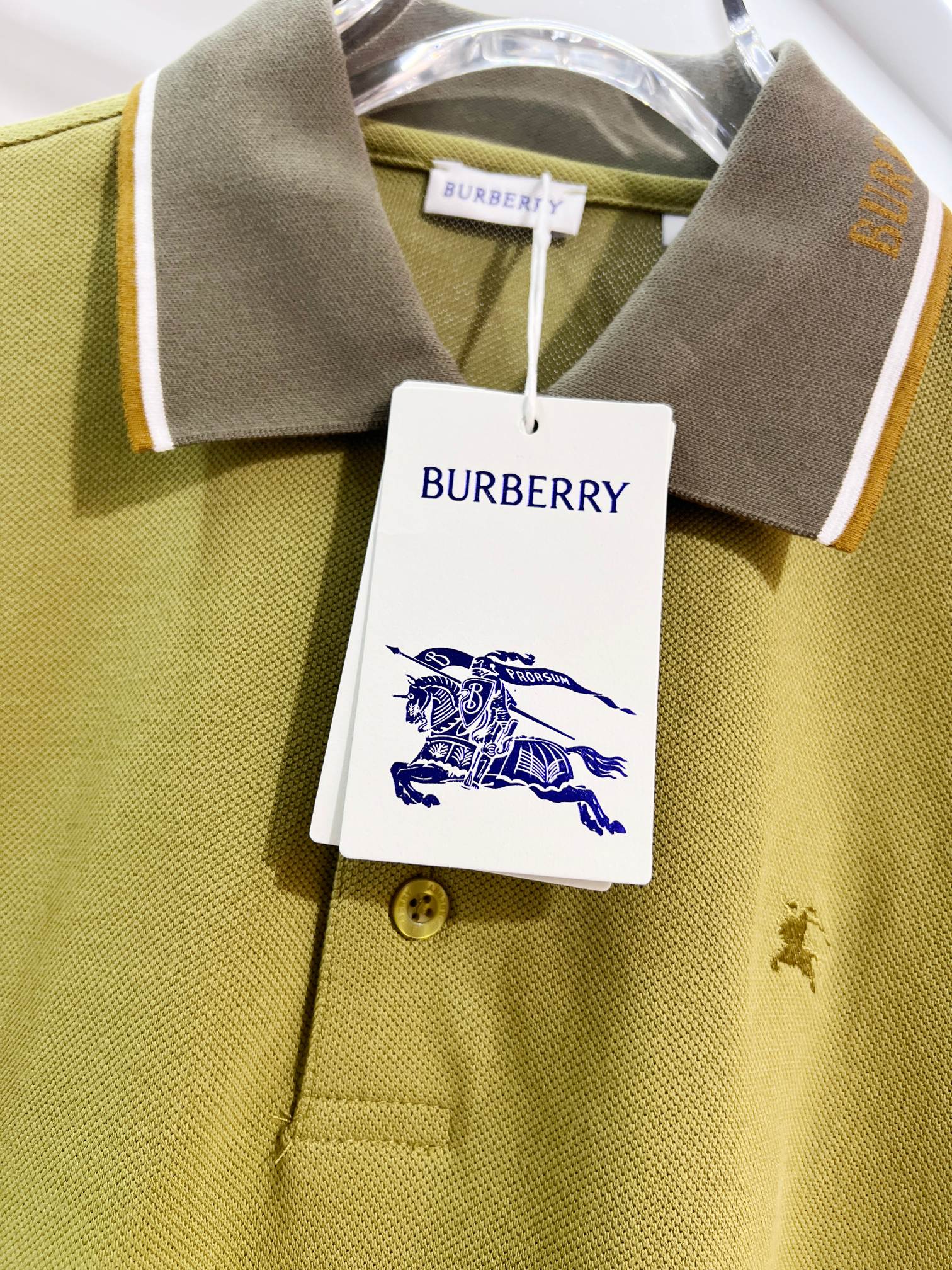 Olive green polo collar with tan inner trim, button placket, and small logo