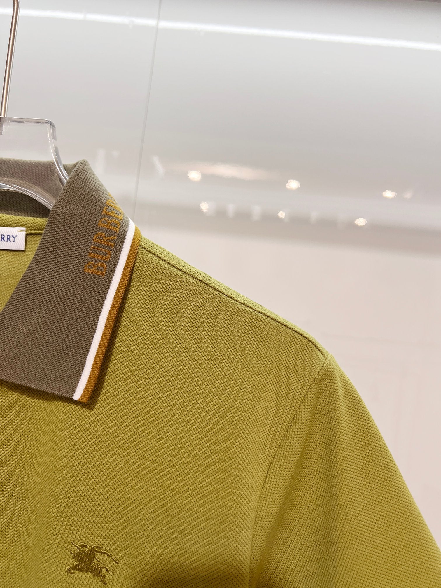 Olive green polo sleeve with embroidered horse logo and contrast collar edge