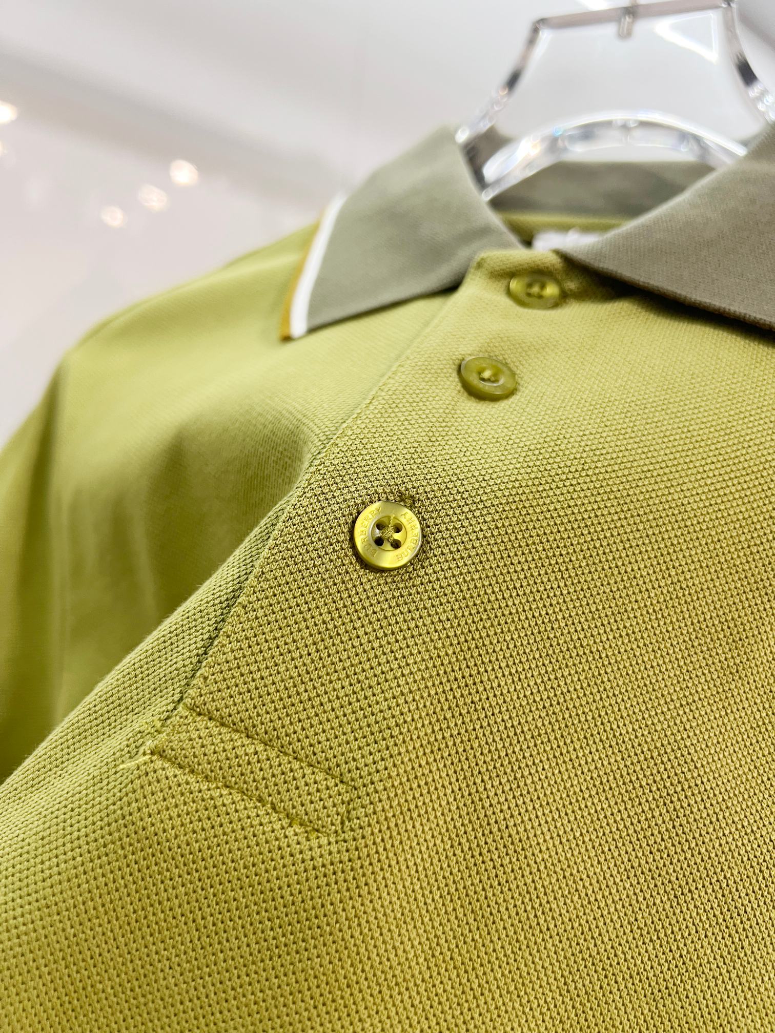 Olive green polo front with two-button placket and embroidered logo on chest